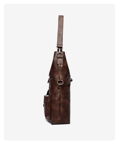 Detail of dark brown leather tote showing side zipper pocket and silver metal D-ring