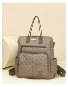 Detail of khaki quilted nylon backpack with metal logo plate and zip pockets