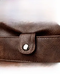 Detail of dark brown lychee grain leather stitching and round metal decorative buckle