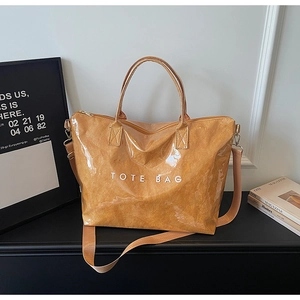 Detailed shot of brown glossy Tyvek tote bag with zipper closure and crossbody strap