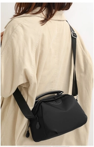 Black Oxford cloth shoulder bag shown with adjustable strap on a casual model outfit