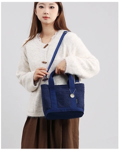 Dettaglio della borsa in pile blu navy con ciondolo a M dorato e tracolla lunga