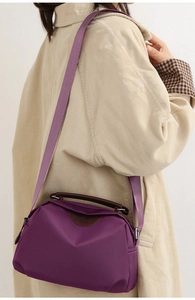 Side view of a purple nylon crossbody bag with brown leather handles on a model