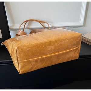 Detail of orange DuPont paper tote bag showing crinkled texture and adjustable strap