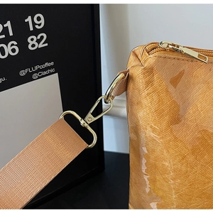 Detail of caramel tote bag featuring golden lobster clasp and glossy textured fabric