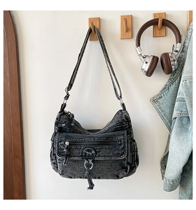 Detail of washed denim crossbody bag featuring multi-pocket design and fringe tassel
