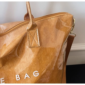 Detail of waterproof PVC tote bag with leather texture and E BAG lettering print