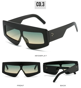 Macro display of black geometric sunglasses with green gradient lenses and metal rivet details