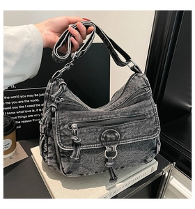 Detail of vintage washed gray denim crossbody bag with multiple zipper pockets