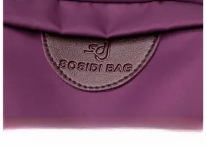 Detail of embossed logo on purple nylon and leather patchwork tote bag surface