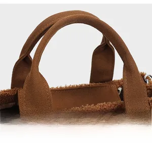 Primo piano dei manici larghi in tela e del morbido tessuto teddy della borsa marrone