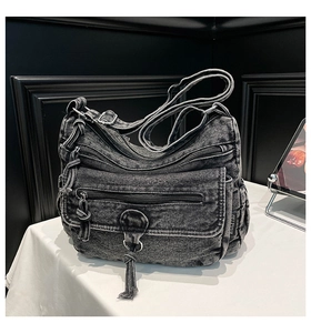 Detailed macro of vintage washed denim crossbody bag showing multi-zipper layers and texture