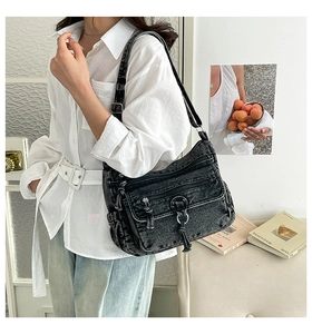 Detail of black washed denim crossbody bag featuring multiple zipper pockets and silver metal hardware