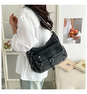 Detail of vintage washed black denim shoulder bag with multiple functional zip pockets