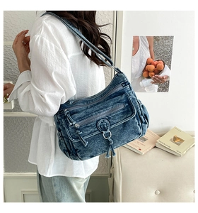 Detail of vintage washed blue denim shoulder bag with multi-zipper pockets and tassels