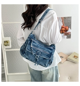 Detail shot of multi-layered blue denim crossbody bag featuring zippers and silver buckles