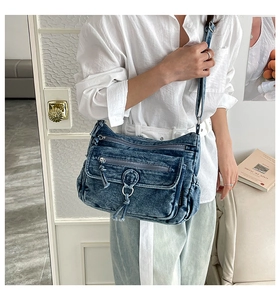 Detail of blue denim crossbody bag with multiple zippers and adjustable shoulder strap