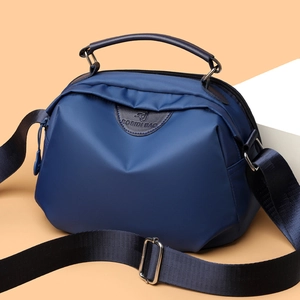 Minimalist navy blue nylon handbag with leather handles and adjustable shoulder strap