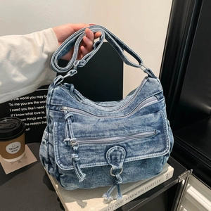 Frayed denim crossbody bag with multiple zippers and adjustable strap in casual style