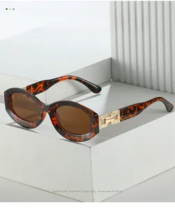Detail of tortoise frame sunglasses with gold H-shaped hinge on white stone base