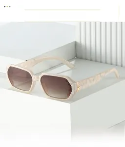 Close-up of geometric cream marble sunglasses with gradient brown lenses and metal hinges