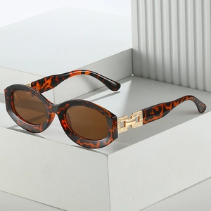 Retro tortoiseshell oval sunglasses with hollow gold metal temples on a white podium