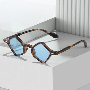 Fashionable tortoise shell sunglasses with blue geometric diamond lenses on a white pedestal