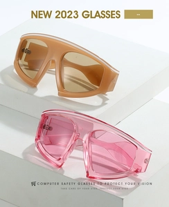 Pink and khaki oversized sports sunglasses displayed on white geometric display blocks