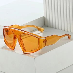 Modern amber oversized cycling sunglasses with a minimalist frame on white geometric stand