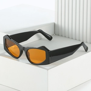 Modern geometric sunglasses with black frame and orange lenses on a minimalist white stand