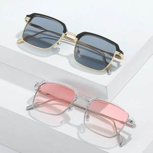 Moderne quadratische Sonnenbrillen in Schwarz-Gold und Transparent-Rosa auf weißen Blöcken