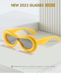 Detail of yellow wrap-around Y2K sunglasses on white geometric display stand