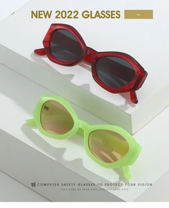 Close-up of translucent red and neon green geometric sunglasses on a minimalist white stand