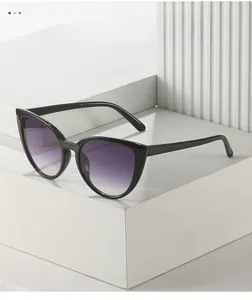 Détail de lunettes œil de chat noires avec verres dégradés violets sur socle blanc