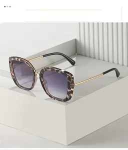 Detail of square leopard print sunglasses with gold metal temples on a white platform