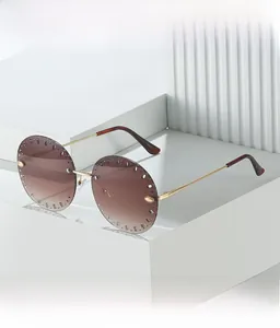 Détail de lunettes de soleil rondes sans monture avec verres dégradés et décor doré