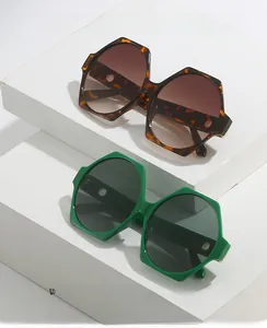 Oversized geometric sunglasses in tortoiseshell and vibrant green frames on stone props