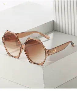 Detail of amber tortoiseshell geometric sunglasses with gold metal hinge accents