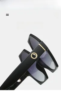 Detail of glossy black sunglasses frame with gold rivet hinges and flexible temple structure