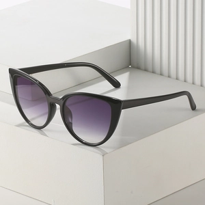 Lunettes de soleil œil de chat à monture noire et verres dégradés violets sur socle blanc