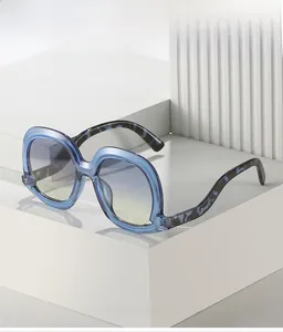Détail des verres dégradés bleus et branches marbrées sur lunettes de soleil oversize