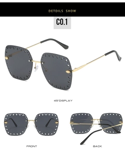 Close-up of rimless sunglasses with gold laser-cut hollow edges and dark grey lenses
