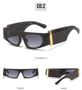 Close-up of flat top sunglasses with dark marble frame and gold metal hinge details