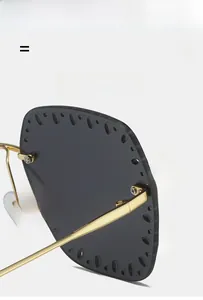 Close-up of rimless grey sunglasses with hollowed-out edges and slim gold metal temples