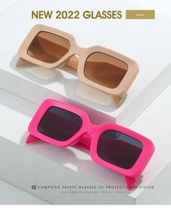Close-up of rectangular sunglasses in nude and magenta on minimalist stone steps