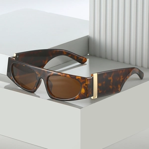 Flat top tortoiseshell sunglasses with wide temples and gold metal accents on white stand