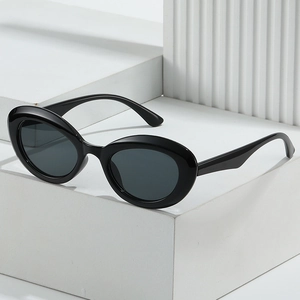 Lunettes de soleil ovales rétro avec monture noire épaisse sur un support géométrique blanc