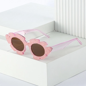 Pink glitter flower-shaped cat-eye sunglasses for women with brown lenses on white display