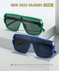 Macro detail of oversized flat top sunglasses in green and blue frames on white blocks