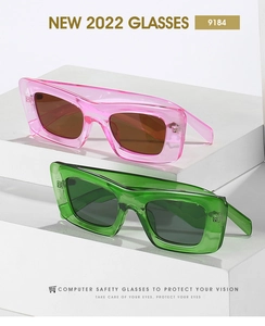 Close-up of pink and green transparent thick frame cat-eye sunglasses on geometric blocks